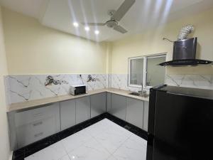 uma cozinha com balcões brancos e um frigorífico preto em Kharian-Inn Hotel em Khāriān