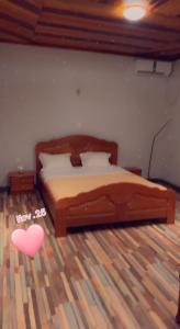 een slaapkamer met een houten bed met een hart op de vloer bij RESIDENCE LUXUEUSE BANGANGTE in Bangangté