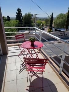 Una mesa y sillas rosas en un balcón. en Departamentos Alto Mendoza, en Las Heras