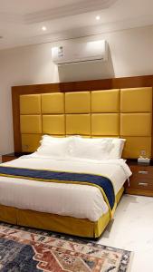 um quarto com uma cama grande e uma cabeceira amarela em HOLIDAy فاملي الطائف em Taif
