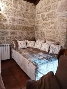 ein Sofa in einem Zimmer mit einer Steinmauer in der Unterkunft Casa de Férias do Parque da Peneda Gerês in Vila Verde + 77 Fotos