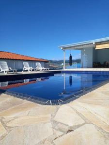 - une piscine avec 2 chaises et une maison dans l'établissement Chácara Aloés - suíte com ar cond banheira hidromassagem, à Socorro