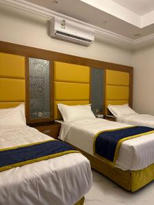 two beds in a room with yellow headboards at HOLIDAy فاملي الطائف in Taif