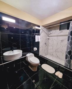 un bagno bianco e nero con servizi igienici e lavandino di Hotel del Valle a Huancayo