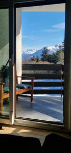 a sliding glass door with a bench on a balcony at Cozy Studio Retreat - completely renovated in a perfect location in Crans-Montana