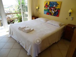 Un dormitorio con una cama blanca con toallas. en Hotel Aquarella en Punta del Diablo