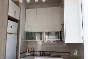 een keuken met witte kasten en een wastafel bij Apartmani Beograd - Light Oasis in Belgrado