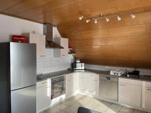 cocina con electrodomésticos blancos y techo de madera en Ferienappartement Grüner Elch, en Rheinhausen
