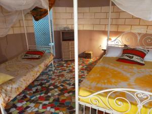 two beds in a room with a mosaic floor at Campement Baobab in Poponguine