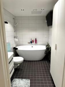 ein Badezimmer mit einer weißen Badewanne und einem WC in der Unterkunft Økern/Premium 3-roms + Garasje in Oslo