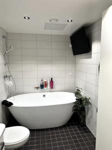 ein Badezimmer mit einer weißen Badewanne und einem WC in der Unterkunft Økern/Premium 3-roms + Garasje in Oslo