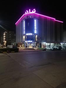 a large building with purple lights on it at night at درر بيان in Hafr Al-Batin