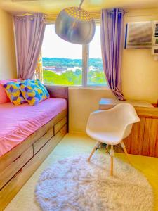 ein Schlafzimmer mit einem Bett, einem Stuhl und einem Fenster in der Unterkunft Urban Oasis Condo Near Ayala Mall Centrio 2 in Cagayan de Oro