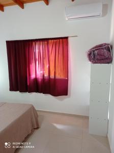 Schlafzimmer mit einem Fenster mit roten Vorhängen in der Unterkunft Complejo Valhalla 4 a 300 mts de la PLAYA in Mar Azul