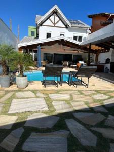 um pátio com duas cadeiras e uma piscina numa casa em Linda casa em Barra do Una em São Sebastião