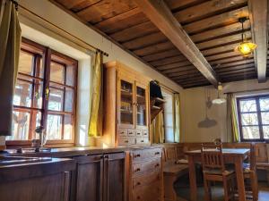 a kitchen with wooden cabinets and a table and a dining room at Apartmány Červený Dvůr in Chvalšiny