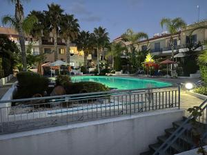 a swimming pool in a resort with palm trees and buildings at Exceptional townhouse in Paphos City
