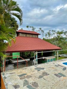 a building with a red roof next to a pool at Exclusiva casa de campo con Piscina in Pedro Brand
