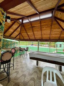 a covered patio with a table and chairs and a piano at Exclusiva casa de campo con Piscina in Pedro Brand