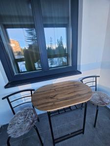 mesa y 2 sillas con mesa y ventana en Apartman Novak en Jahorina