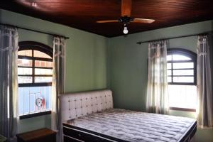 ein Schlafzimmer mit einem Bett und zwei Fenstern in der Unterkunft Casa 46 in São Sebastião