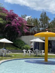 a man standing next to a pool with chairs and umbrellas at Gravatá - Apartamento Família no Monte Castelo in Gravatá