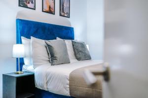a bedroom with a bed with a blue headboard and pillows at Waterhouse Suite - Modern 2 Bed in Manchester City Centre- Perfect for Family, Business and Leisure Stays by Dreamluxe in Manchester