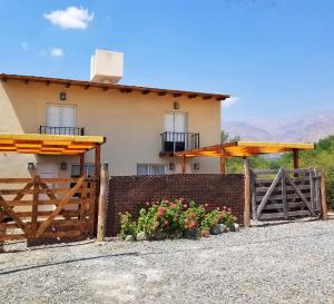 a house with a fence and flowers in front of it at Malvón in Cafayate