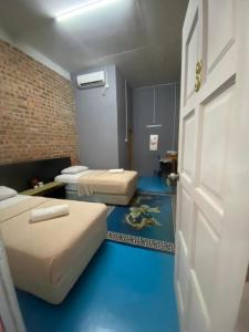 2 camas en una habitación con suelo azul y puerta en Naja Hotel, en Kampung Rahmat