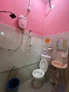 Baño de color rosa con aseo y lavamanos en Naja Hotel, en Kampung Rahmat