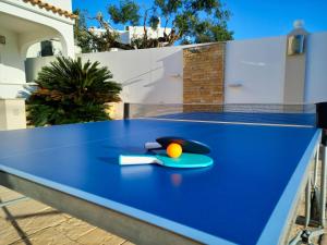 una mesa de ping pong azul con una pelota. en Villa with pool and sea view with two independent floors en Faro