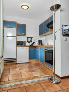 kuchnia z niebieskimi szafkami i białą lodówką w obiekcie Godewind w mieście Wyspa Poel