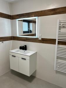 een badkamer met een witte wastafel en een spiegel bij The Houses - Chata u sjezdovky 2 in Velké Meziříčí