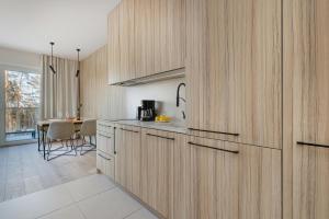 cocina con armarios de madera y mesa en Wyspa Uznam Promenada apartament na Wydmie, en Świnoujście