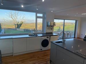 a kitchen with a sink and a large window at Dog friendly, Roof top hot tub, Panoramic views. in Torquay