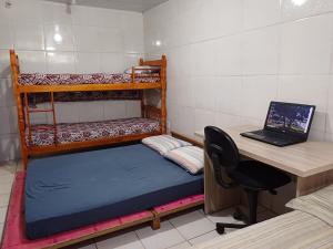 a room with a desk and a bunk bed and a laptop at Recanto Figueira Silvestre in Cidreira