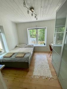 ein Schlafzimmer mit einem Bett in einem Zimmer mit einem Fenster in der Unterkunft Härlig Skärgårdsvilla med strålande sjöutsikt in Dalarö