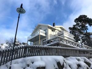 ein schneebedecktes Haus mit einem Zaun und einem Straßenlicht in der Unterkunft Härlig Skärgårdsvilla med strålande sjöutsikt in Dalarö
