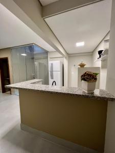 a large kitchen with a counter and a refrigerator at Zaffir Apartamento in Cuiabá