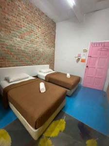 2 camas en una habitación con una pared de ladrillo en Naja Hotel, en Kampung Rahmat