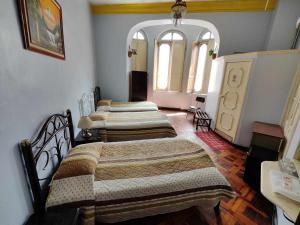 eine Gruppe von 4 Betten in einem Zimmer in der Unterkunft Hostal Juana de Arco in Quito