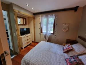 1 dormitorio con 1 cama, vestidor y TV en Petite chambre cosy avec salle de bain privative en Saint-Pierre-dels-Forcats