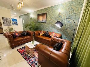 a living room with brown leather couches and a table at Panaromic Perch in Lucknow