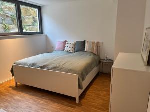 ein weißes Schlafzimmer mit einem Bett mit Kissen darauf in der Unterkunft Ruhige Ferienwohnung in Oberhaching bei München in Oberhaching