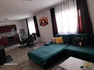 a living room with a green couch and a kitchen at Apartman T&N 