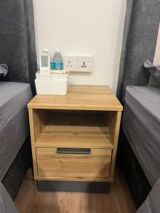 a wooden night stand with a drawer next to two beds at KIWI INN in Taiping
