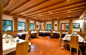 a restaurant with white tables and chairs and windows at Berghotel zum Zirm in Collalbo