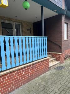 a brick house with a blue railing on a porch at Ferienwohnung am Moor in Rehden
