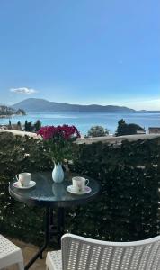 un tavolo con due tazze e un vaso con fiori di Sea Apartment Igalo a Herceg-Novi