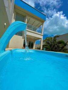 - une piscine avec une fontaine en face d'une maison dans l'établissement Casa de temporada Camocim, à Camocim